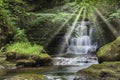 Majestic waterfall in forest landscape image with added drama of sun beams breaking through trees in woodland Royalty Free Stock Photo