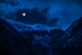Majestic winter night in a mountain valley with full moon in a starry sky