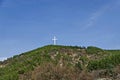 A majestic wooden cross rises over a hill overgrown with coniferous and deciduous trees against the blue sky near Blagoevgrad