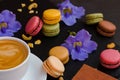 Makarons with cup of your favorite coffee and blue flowers on a black stone background. It`s really amazing morning.