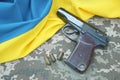 A Makarov pistol with cartridges against the background of a military camouflage pixel and the flag of Ukraine. Royalty Free Stock Photo