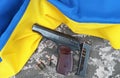 A Makarov pistol with cartridges against the background of a military camouflage pixel and the flag of Ukraine. Royalty Free Stock Photo