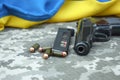 A Makarov pistol with cartridges against the background of a military camouflage pixel and the flag of Ukraine. Royalty Free Stock Photo