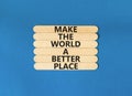 Make a better world symbol. Concept words Make the world a better place on wooden stick. Beautiful blue table blue background.
