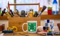 Make do and mend logo on coffee mug surrounded by tools on cafe table top at repair cafÃÂ©, consumer activism, homespun movement