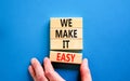 We make it easy symbol. Concept words We make it easy on wooden cubes. Beautiful blue table blue background. Businessman hand.
