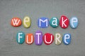 We make future, creative slogan composed with multi colored stone letters over green sand