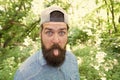 Make life worth living. summer day fun. bearded man looking funny. brunette bearded man wear cap in forest on background