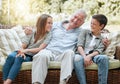 They make me love hard and laugh louder. a senior man sitting outside with his two grandchildren.