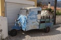 Beat-up old three-wheel truck in back lane in Greece