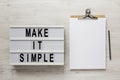 `Make it simple` words on a lightbox, clipboard with blank sheet of paper on a white wooden background, view from above. Top vie Royalty Free Stock Photo