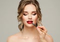 Make up Artist apply Red Lipstick. Beauty Woman Model put on Lip Gloss. Close up Portrait of Professional Makeup Master Hand with Royalty Free Stock Photo