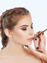 Make-up artist does lips make-up to a woman with smoky eyes makeup. Beautiful portrait of a girl close up. Professional makeup and