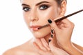 Make-up artist does lips make-up to a woman with smoky eyes makeup. Beautiful portrait of a girl close up. Professional makeup and