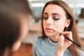 Make up artist hand applying gloss on woman lips Royalty Free Stock Photo