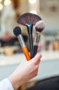 The make-up artist holds in his hand three brushes made of natural bristles for powder, foundation and blush Royalty Free Stock Photo