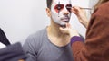 Make-up artist makes greasepaint on man`s face before his performance on scene