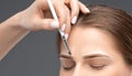 Make-up artist makes markings with white pencil for eyebrow and paints eyebrows. Professional makeup and facial care