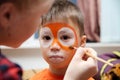 Make up artist making tiger mask for child.Children face painting. Boy painted as tiger or ferocious lion Royalty Free Stock Photo