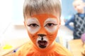 Make up artist making tiger mask for child.Children face painting. Boy painted as tiger or ferocious lion