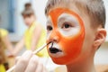 Make up artist making tiger mask for child.Children face painting. Boy painted as tiger or ferocious lion. Preparing Royalty Free Stock Photo