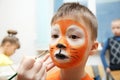 Make up artist making tiger mask for child.Children face painting. Boy painted as tiger or ferocious lion Royalty Free Stock Photo