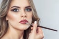 The make-up artist paints the lips of a beautiful woman,  completes the day`s make-up Royalty Free Stock Photo