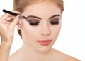 Make-up artist plucks eyebrows with tweezers to a woman with smoky eyes makeup. Beautiful thick eyebrows close up. Professional