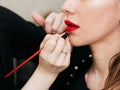 Make up artist puts red lipstick with brush on the lips of a woman Royalty Free Stock Photo