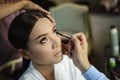 Make up artist putting on mascara on beautiful asian model Royalty Free Stock Photo