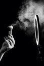 Make-up artist`s hand with makeup brushes in front of a ring lamp against. Black and white photo Royalty Free Stock Photo