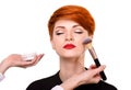 Make-up artist working with brush on model face. Beautiful young woman with short red hair. Royalty Free Stock Photo