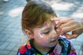 A make-up artist works over the face of a little girl. Child creativity. The master paints a beautiful figure on the face of a