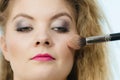 Makeup artist applying with brush rouge on female check Royalty Free Stock Photo