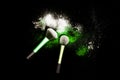 Make-up brush with colorful powder on black background. Explosion stars dust with bright colors. White and green powder. Royalty Free Stock Photo