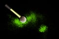 Make-up brush with green powder spilled glitter dust on black background. Makeup brush on new year`s Party with bright colors.