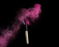 Make-up brush with pink powder explosion on black Royalty Free Stock Photo