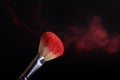 Makeup brush with red powder explosion on black background Royalty Free Stock Photo