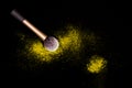 Make-up brush with yellow powder spilled glitter dust on black background. Makeup brush on new year`s Party with bright colors.