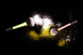 Make-up brushes with colorful powder spilled glitter dust on black background.