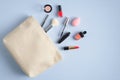 Make-up cosmetic bag on blue background. Stylish makeup artist pouch with beauty products. Flat lay, top view Royalty Free Stock Photo