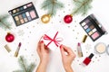Beauty make up cosmetic set with christmas decoration and present in woman`s hands flat lay on white background Royalty Free Stock Photo