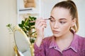 Make-up at home. Young beautiful woman with makeup brush applies eye shadow