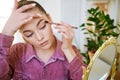 Make-up at home. Young beautiful woman with makeup brush applies eye shadow