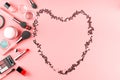 Make up products on pink with confetti heart frame