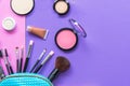 Make up products spilling out of a pastel blue cosmetics bag, on purple and pink background with empty space at side. Royalty Free Stock Photo