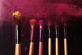 Make-up tools. Brush for makeup. Cosmetic brushes on black with bright dust splash. Colorful pink shadows pigment Royalty Free Stock Photo