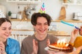 Make a wish. Man wearing party cap blowing out burning candles on birthday cake. Happy Birthday party. Group of friends Royalty Free Stock Photo
