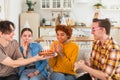 Make a wish. Woman wearing party cap blowing out burning candles on birthday cake. Happy Birthday party. Group of Royalty Free Stock Photo