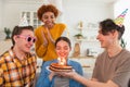 Make a wish. Woman wearing party cap blowing out burning candles on birthday cake. Happy Birthday party. Group of Royalty Free Stock Photo